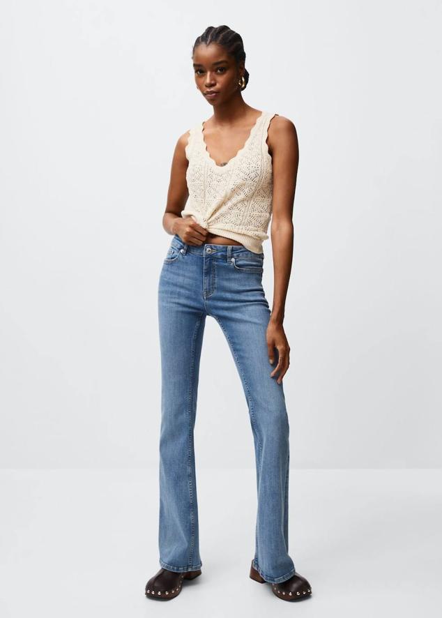 Jeans flare en tejido elástico con tiro medio, pernera recta con bajo acampanado, detalles desgastados y cinco bolsillos, en tono azul medio, de Mango. Los encontrarás a 29,99 euros.