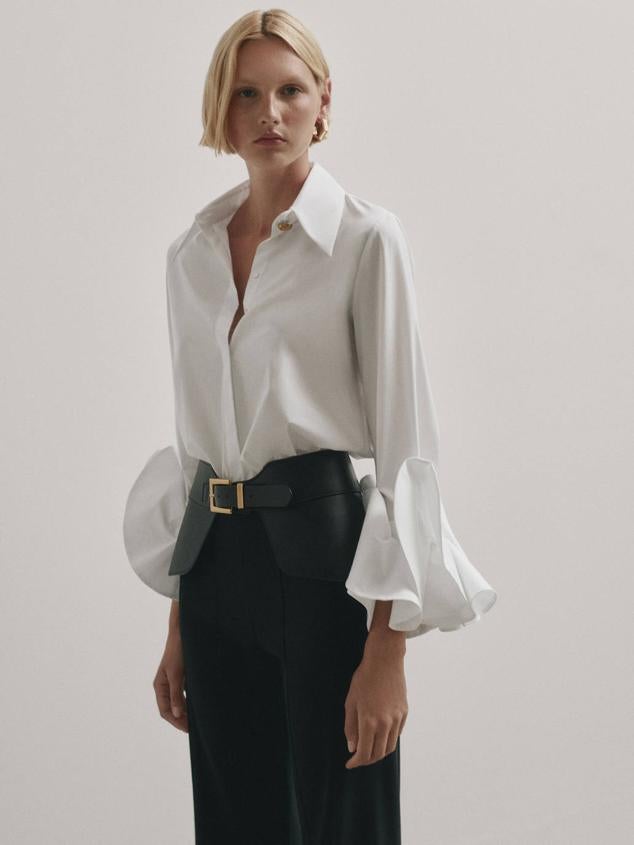 Camisa blanca en tejido de popelín con cuello solapa, cierre de botones y manga estilo amapola con volantes en los puños, de Massimo Dutti. Cómprala a 89,95 euros.