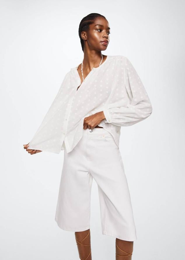 Camisa blanca en tejido mezcla de algodón con detalles bordados de flores, silueta relajada, corte holgado, manga larga, cuello redondo y cierre de botones, de Mango. Puedes comprarla por 39,99 euros.