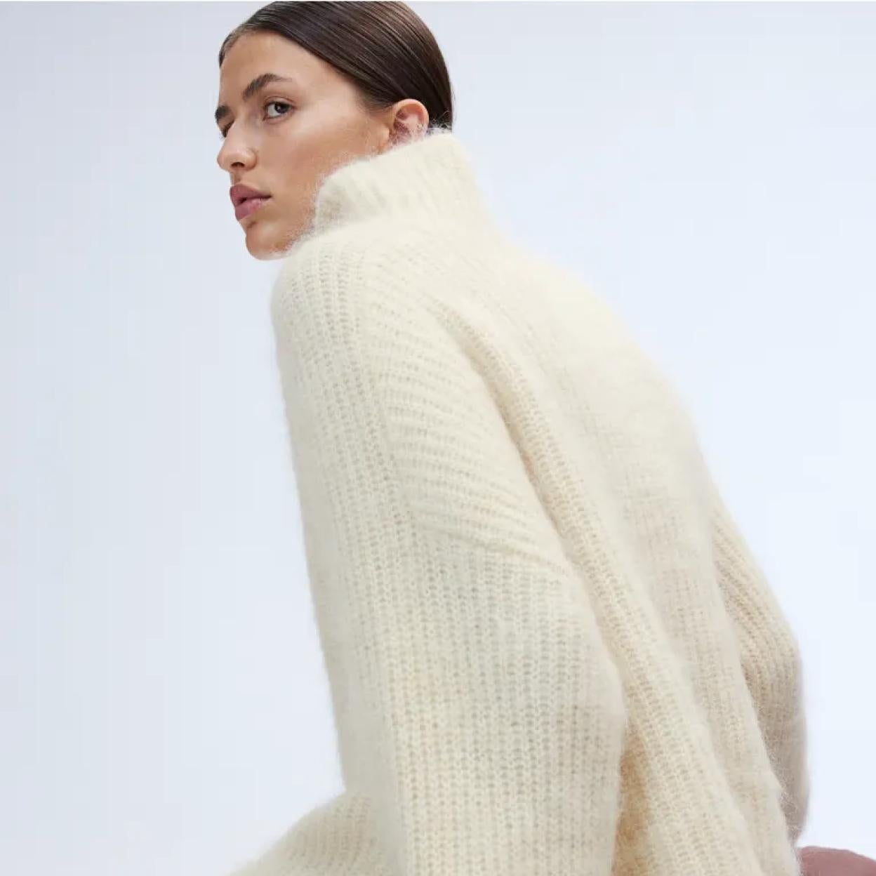 La modelo luce un jersey blanco de lana con flecos que combina con una falda midi de lana con flecos. 