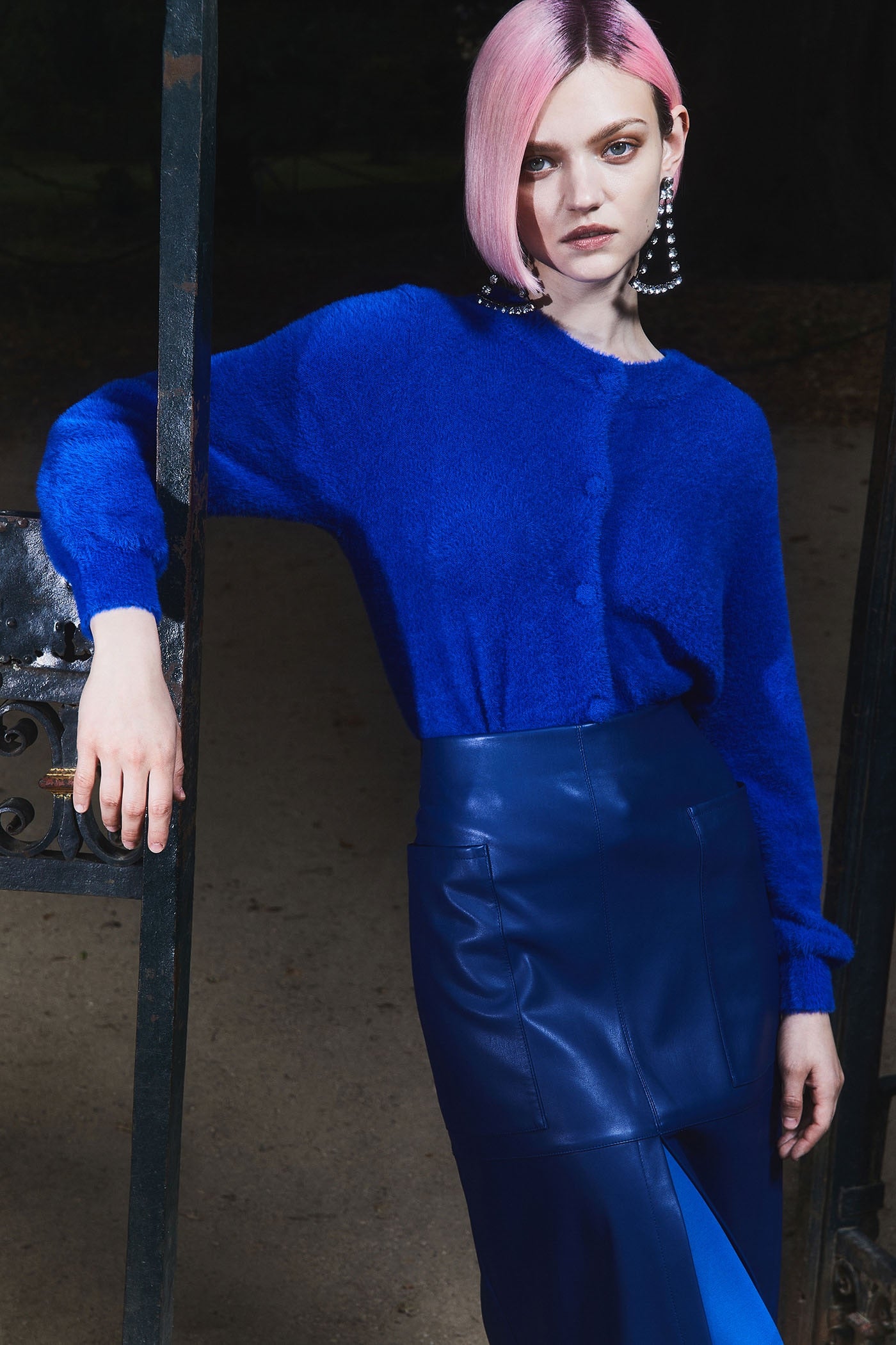 La modelo lleva una falda midi de piel de color azul eléctrico que combina con un jersey de lana del mismo color. 