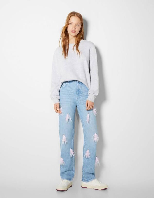 Pantalón vaquero con pernera recta, bolsillos, tiro alto y detalle de plumas rosas y strass, de Bershka. Hazte con ellos por 45,99 euros.