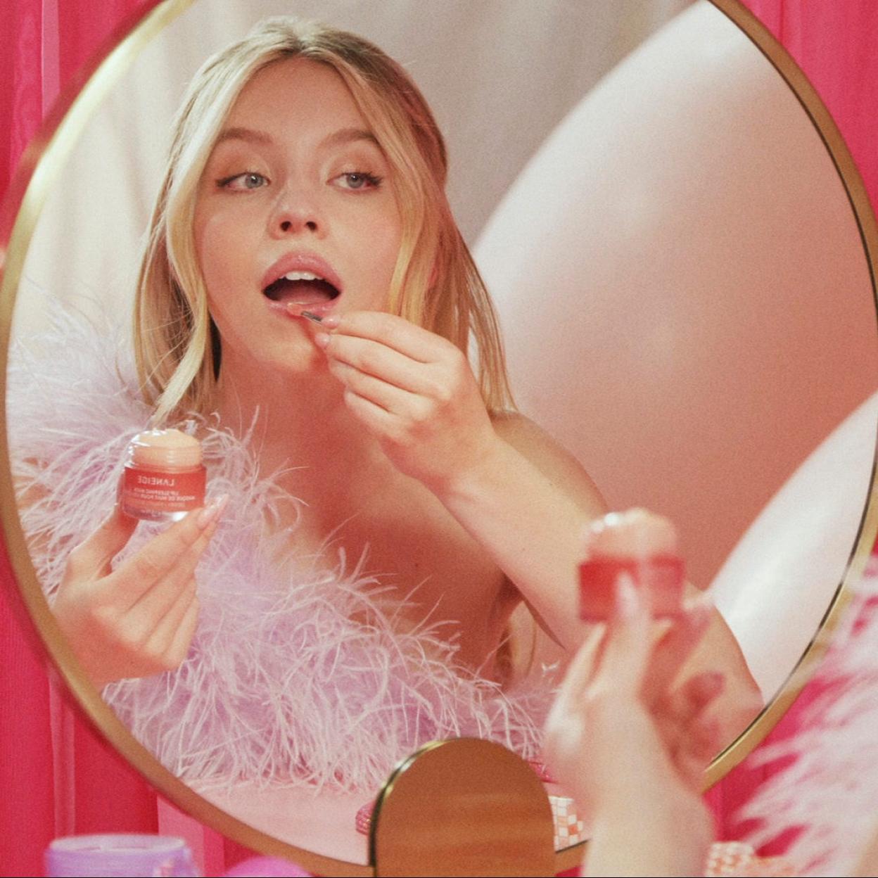 La actriz Sydney Sweeney aplicándose una mascarilla de labios para un resultado jugoso y sin arrugas.