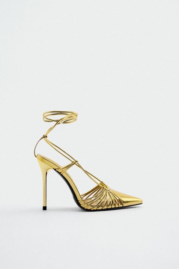 Zapatos de tacón alto terminados en punto con detalle de tiras para anudas y acabado metalizado dorado, de Zara. Están disponibles por 35,95 euros.