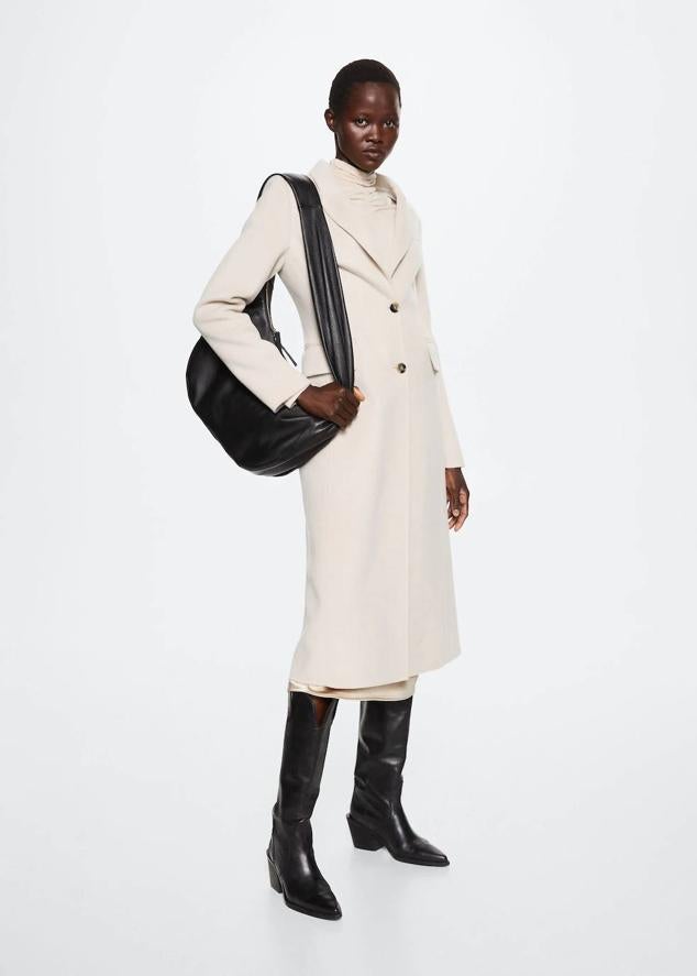 Abrigo largo de lana con diseño entallado handmade, cuello solapa de pico, cierre de botones, bolsillos con tapeta y abertura posterior en el bajo, en tono crudo, de Mango. Su precio es de 169,99 euros.