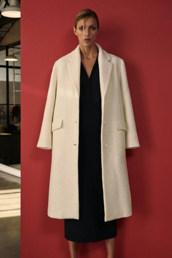 Abrigo recto de corte masculino en tejido de lana texturizada con hombros estructurados, manga larga, cuello solapa y cierre de botones a tono, en crudo, de Zara. Cómpralo a 99,95 euros.