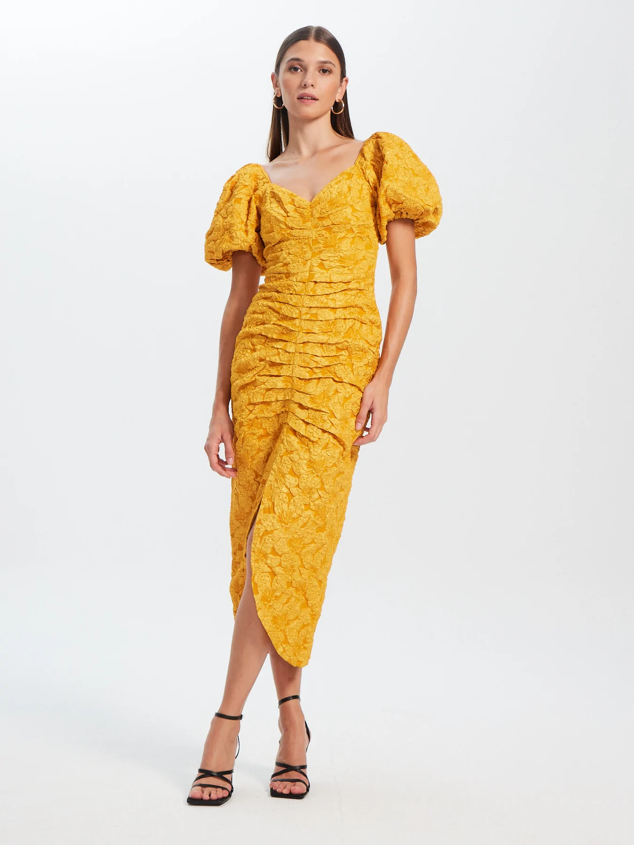 Vestido de corte midi con escote corazón de color dorado. Ideal para tus ocasiones más especiales. Es de Mioh. Precio: 229 €.