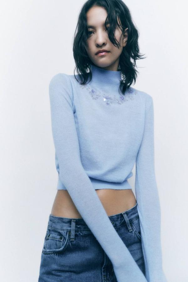 Jersey de punto fino con cuello alto, manga larga y detalle de abalorios a tono, en color azul claro. Cuesta 29,95 euros.