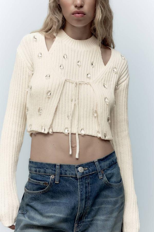 Cárdigan en tejido de punto chenilla acanalado con cierre mediante lazada, manga larga y aplicación de cristales en forma de gota, color crudo. Está disponible a 22,95 euros.