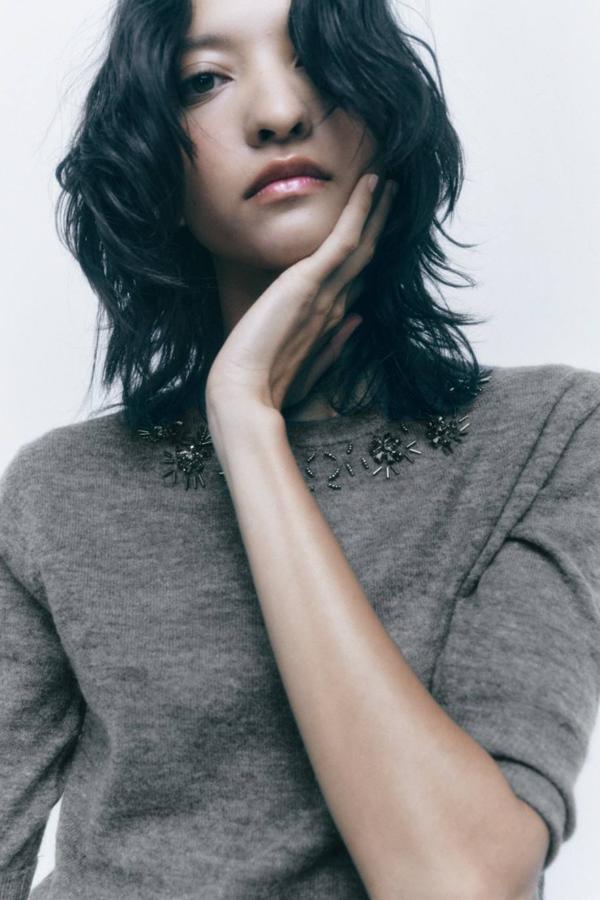 Jersey de punto suave con manga corta y cuello redondo decorado con detalle de abalorios a tono, color gris. Está disponible por 29,95 euros.