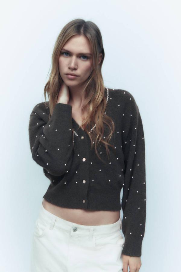 Cárdigan de punto suave con corte relajado, manga larga, cuello de pico decorado con hilera de brillantes y apliques de perlas en el cuerpo, en gris oscuro. Hazte con él por 35,95 euros.