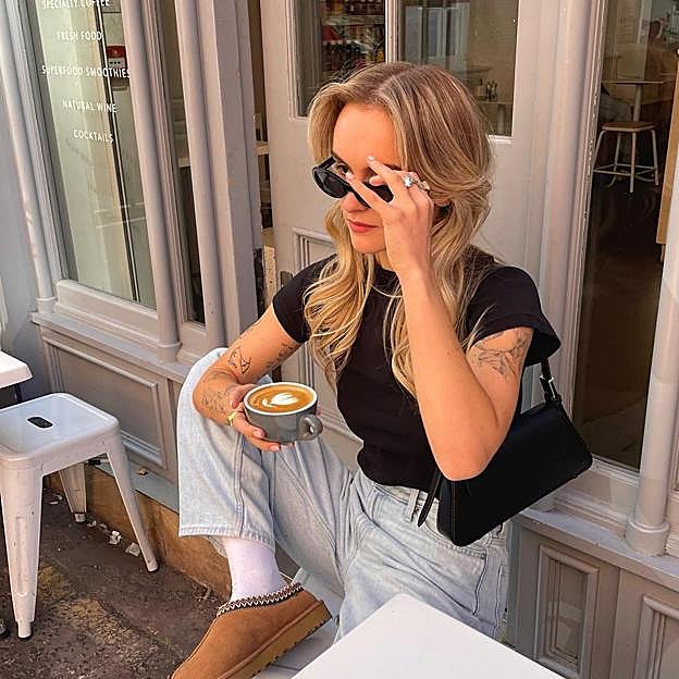 Influencer con camiseta negra, vaqueros y zapatillas Ugg.