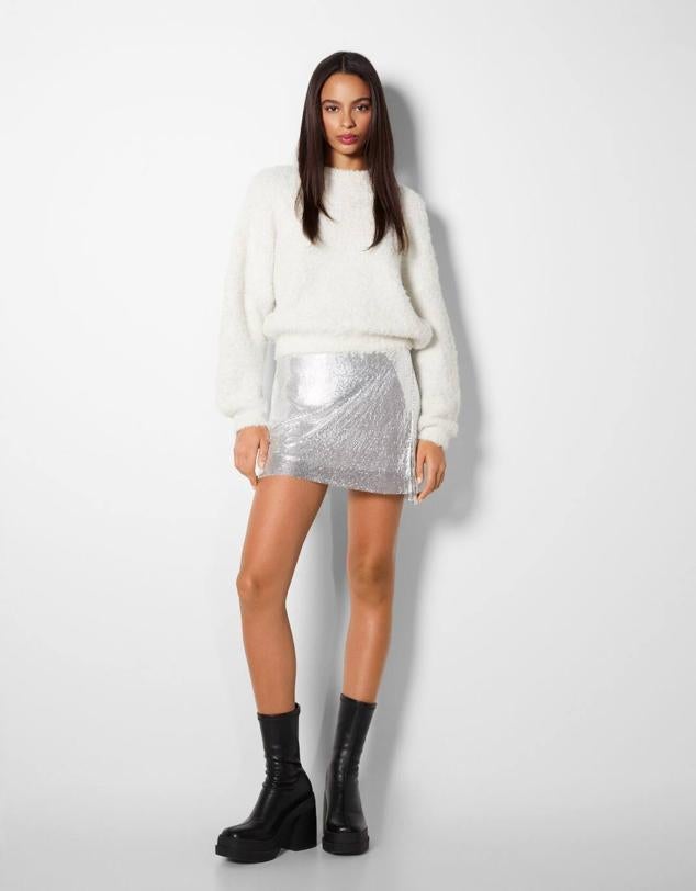 Minifalda en tejido brillante de malla metalizada con tiro alto y abertura laterales, en plateado, de Bershka. Hazte con ella por 79,99 euros.