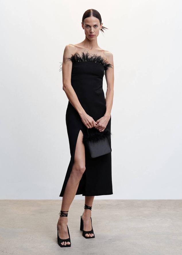 Vestido midi en tejido fluido con diseño cruzado, escote palabra de honor, abertura en el bajo y adorno de plumas desmontable, color negro, de Mango. Encuéntralo por 79,99 euros.
