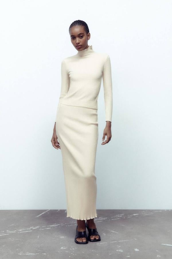 Falda larga confeccionada en tejido de punto canalé con tiro alto, cintura elástica, corte entallado y abertura trasera en el bajo, color crudo, de Zara. La encontrarás por 17,95 euros.