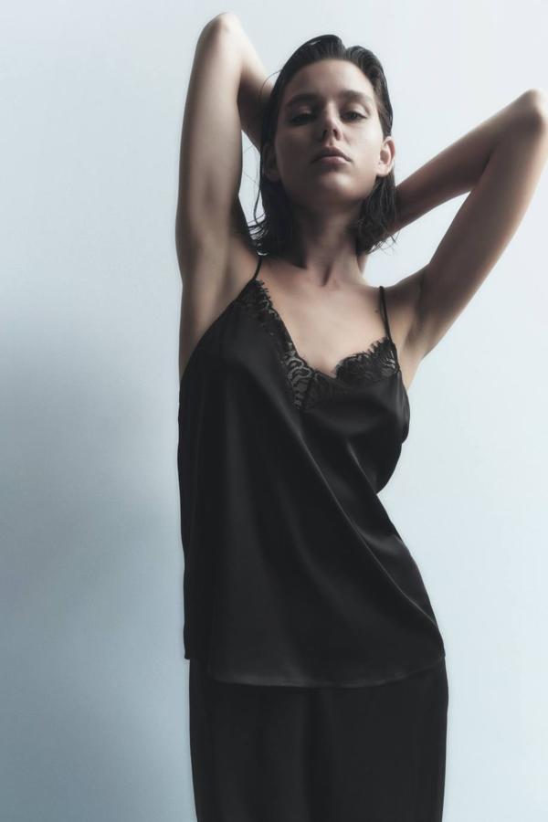 Top lencero en tejido satinado con tirantes finos y encaje a combinación en el escote, color negro, de Zara. Cuesta 22,95 euros.