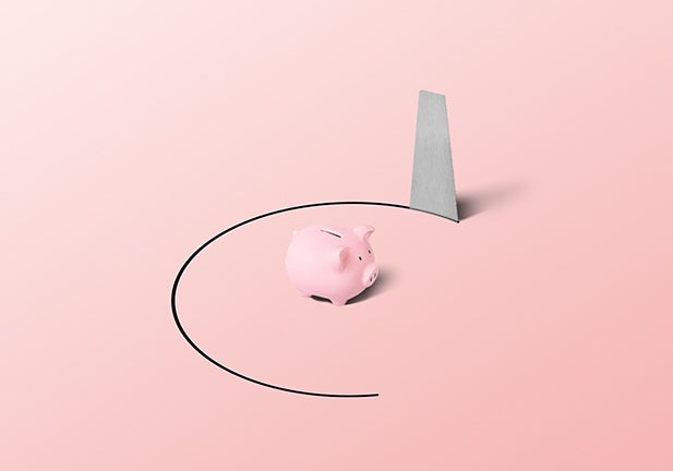 Piggy bank in a trapped position with a hand saw. Could illustrate volatile and risky savings and investments or a market that's about to collapse shown in a conceptual way