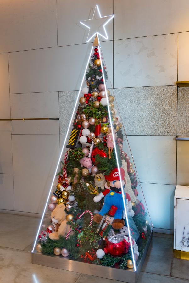 Stella McCartney utiliza la nostalgia británica con un árbol lleno de regalos en su interior, entre los que destacan juguetes infantiles de los años 90.