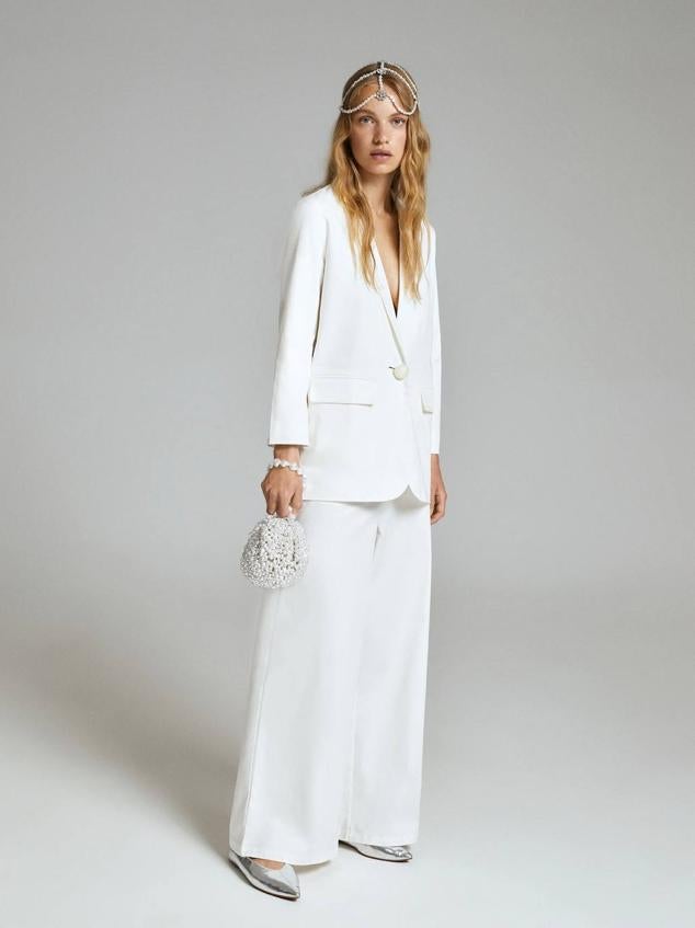 Traje compuesto por blazer relajada con botón de perla y pantalones de vestir anchos, color blanco. Tiene un coste de 59,99 euros y 35,99 euros.