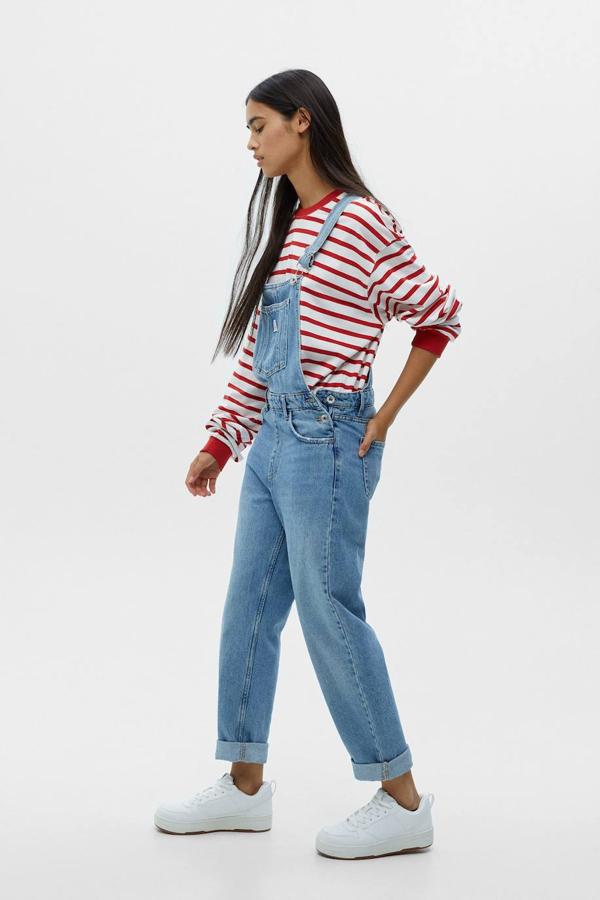 Peto vaquero relaxed fit con tirantes anchos ajustables, bolsillos, escote recto y perneras con acabado en vuelto, en azul, de Pull&Bear. Está disponible por 29,99 euros.