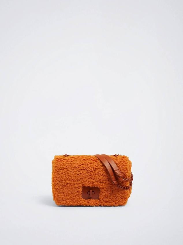 Bolso de hombro rectangular de tamaño mediano en tejido de borreguillo con doble asa y cierre de solapa con broche, de Parfois. Está disponible en crudo, naranja y morado, por 22,99 euros.