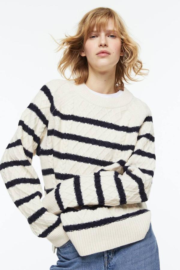 Jersey de punto trenzado con corte relajado, cuello redondo, manga larga y estampado a rayas en blanco y azul marino, de H&M. Puedes encontrarlo a 34,99 euros.