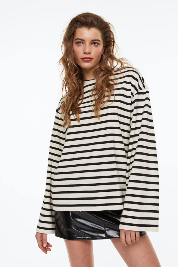 Jersey en tejido de punto suave con cuello redondo, manga larga ancha y corte relajado, en estampado a rayas crudo y negro, de H&M. Cuesta 29,99 euros.
