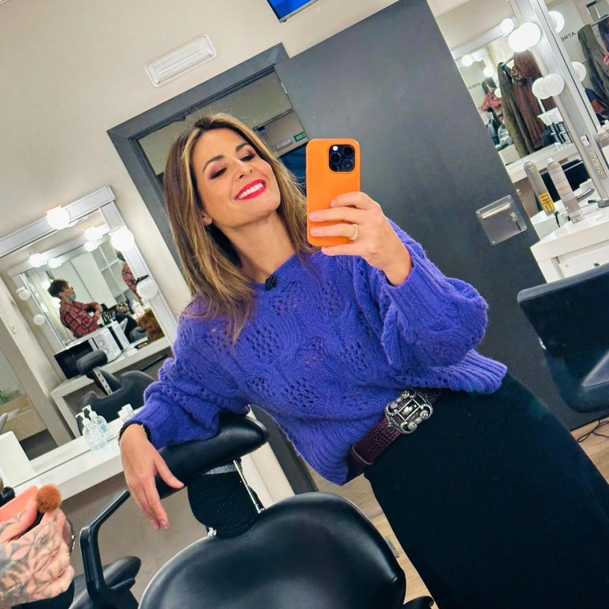 Nuria Roca haciéndose un selfie con jersey de punto y falda midi de Mango.