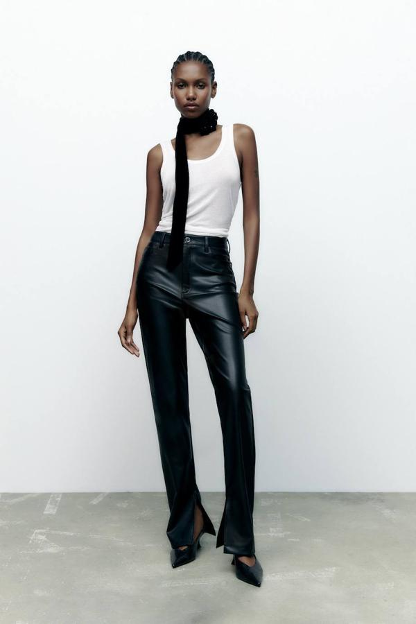 Pantalones slim flare en tejido efecto piel con tiro alto, bolsillos, trabillas y bajo acabado en abertura, en negro, de Zara. Cuestan 25,95 euros.