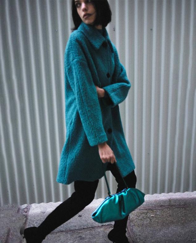 Abrigo midi en tejido bouclé con cuello solapa, corte recto, cierre de botones y bolsillos laterales, en tono verde azulado, de Sfera. Lo comprarás a 69,99 euros.