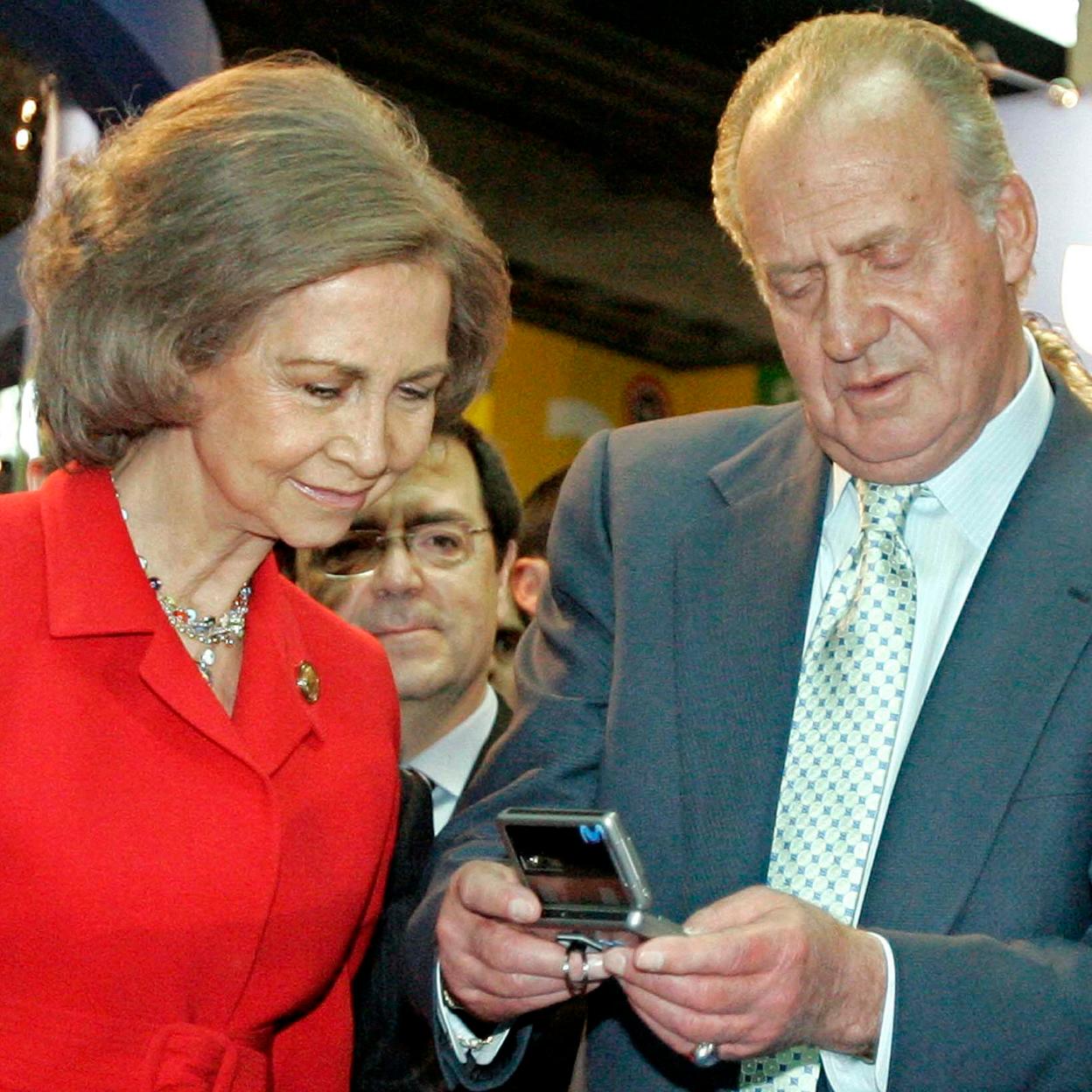 La reina Sofía y Juan Carlos I miran un teléfono.