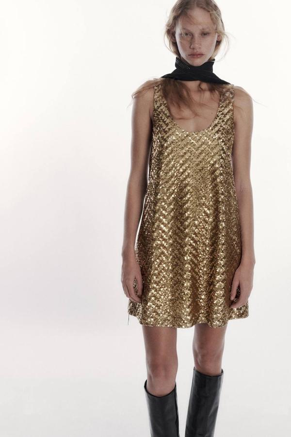 Vestido corto en tejido de punto con aplicación de lentejuelas, escote redondo y tirantes anchos, dorado, de Zara. Lo encontrarás a 49,95 euros.
