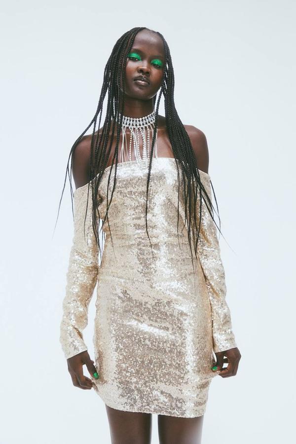 Vestido corto ajustado con hombros al descubierto, manga larga y tejido de lentejuelas dorado, de H&M. Tiene un coste de 29,99 euros.