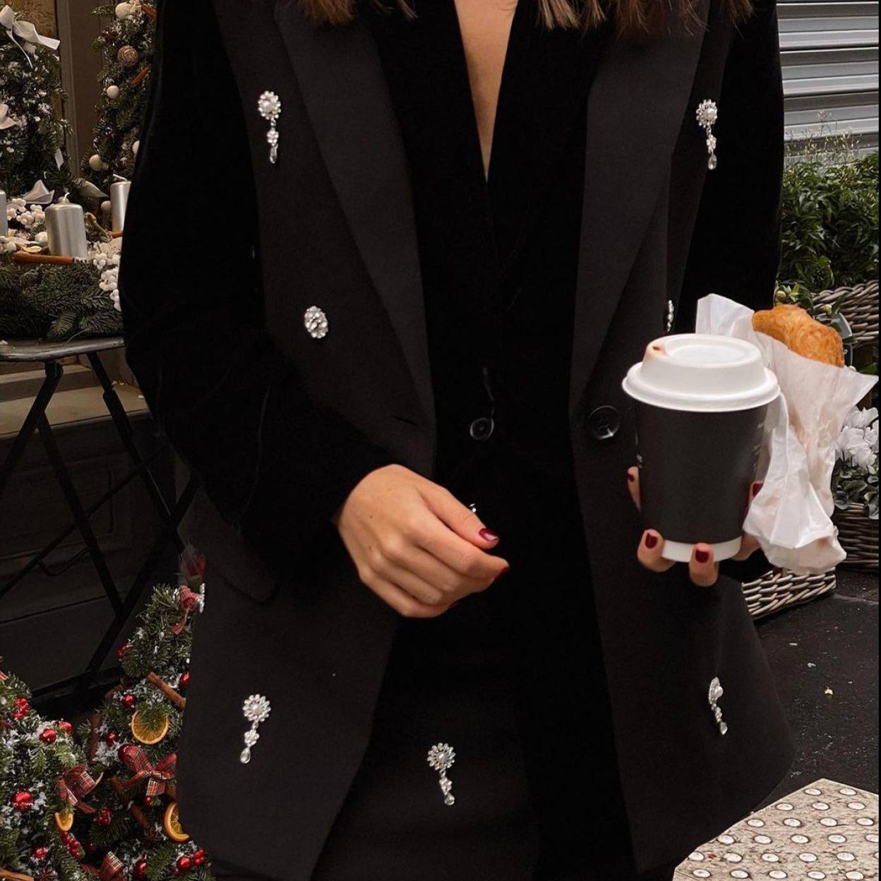 La influencer lleva un conjunto negro de chaleco y falda con detalles de joyas