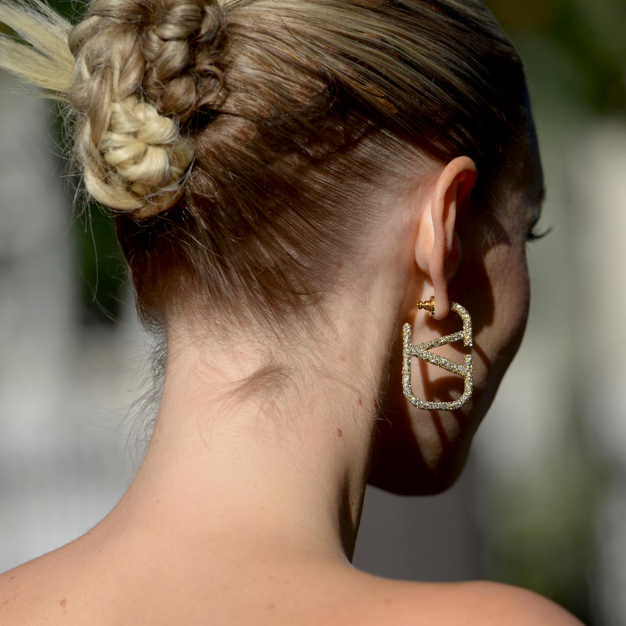 Una mujer con pendientes en color dorado.