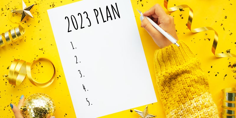 Writing New Year plan 2023. Merry Christmas coming concept. Decorations for Christmas tree on yellow background.