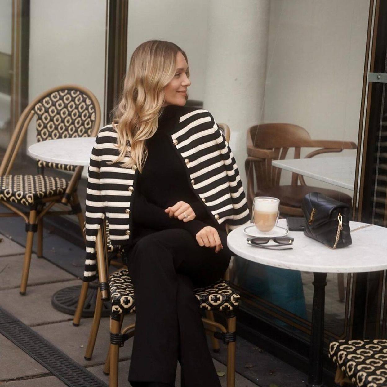 La influencer lleva un total look negro con chaqueta de rayas