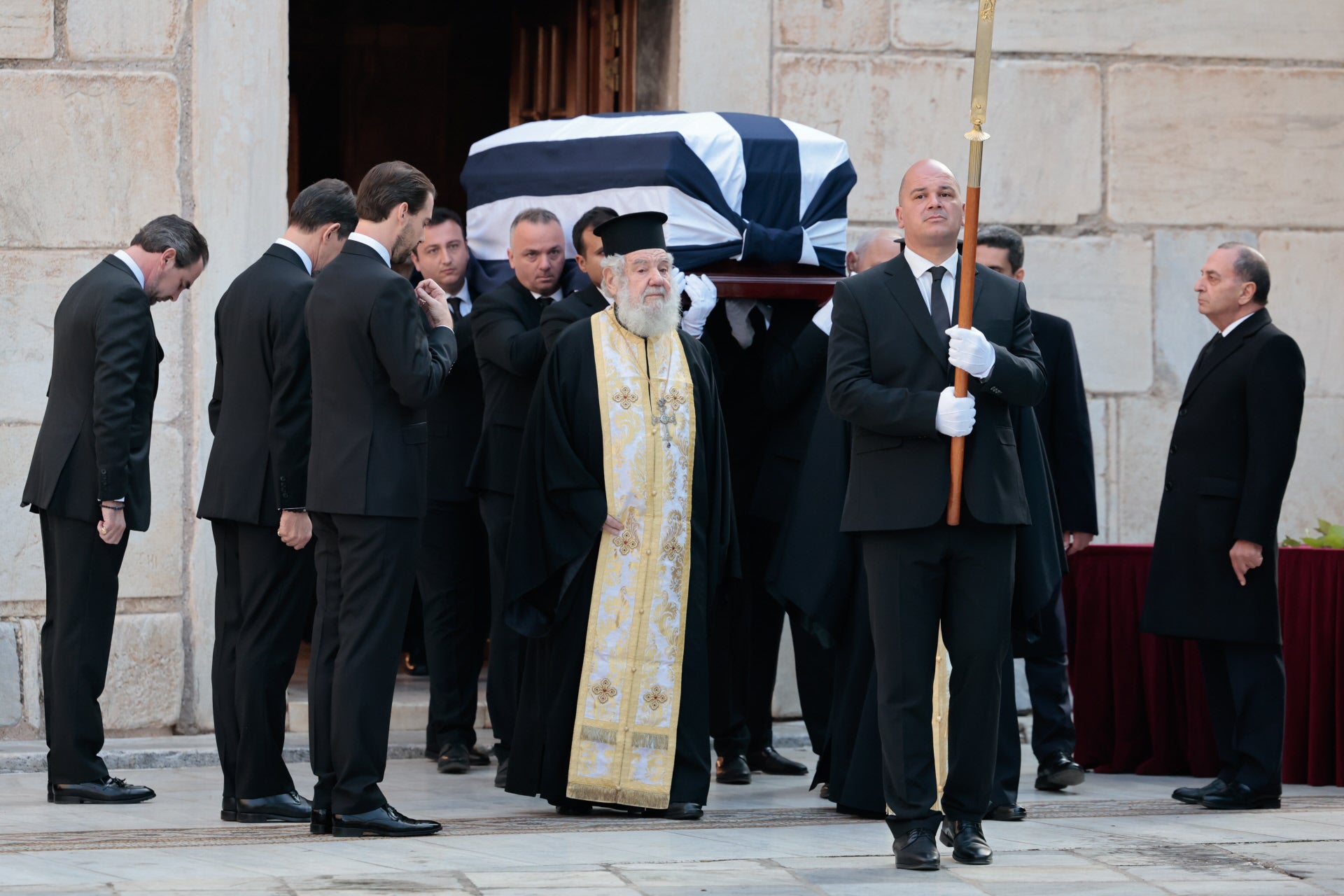 Los hijos de Constantino de Grecia, Pablo, Philippos y Nicolás, muestran sus respetos al paso del ataud donde ya descansan los restos de su padre, a la salida del templo.