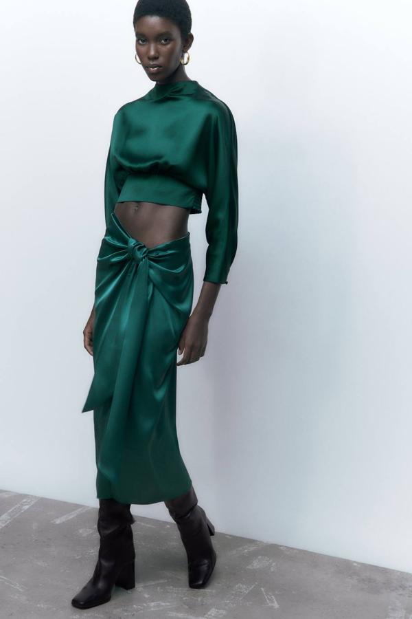 Falda midi en tejido satinado con tiro alto y detalle de nudo frontal con abertura, en verde, de Zara. La comprarás rebajada a 17,99 euros.