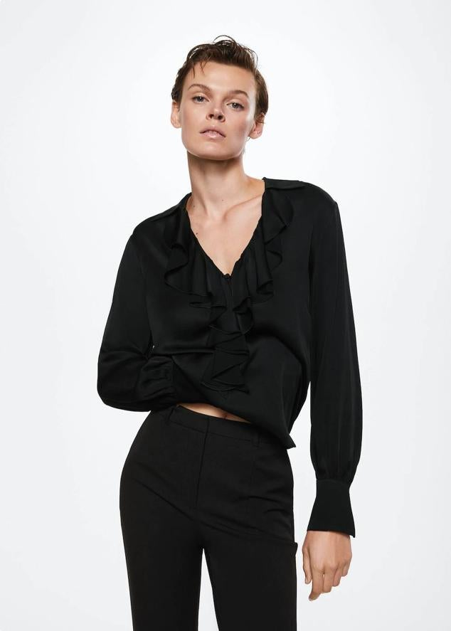 Blusa satinada con escote de pico, manga larga acabada en puño y volantes, en negro, de Mango. Tiene un coste rebajado de 29,99 euros.