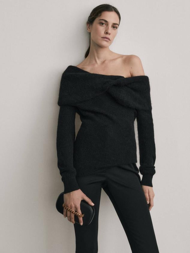 Jersey en tejido de punto soft con cuello barco retorcido, hombros al descubierto y manga larga. Está disponible en negro, crudo y lila, por 129 euros.