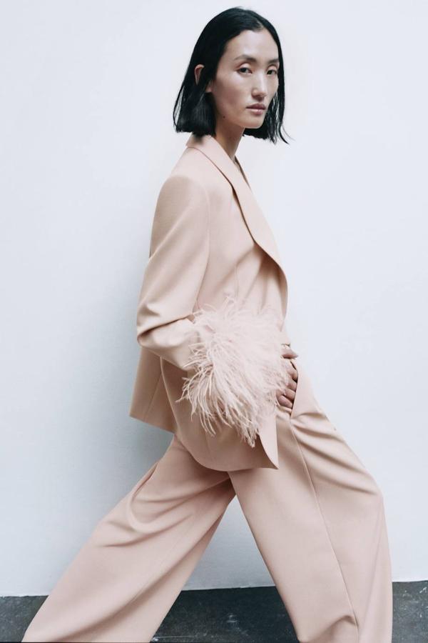 Traje con blazer decorada con plumas a tono en los puños y pantalón ancho con pinzas, tono rosa empolvado, de Zara. Puedes comprarlo a 109 euros y 49,95 euros.