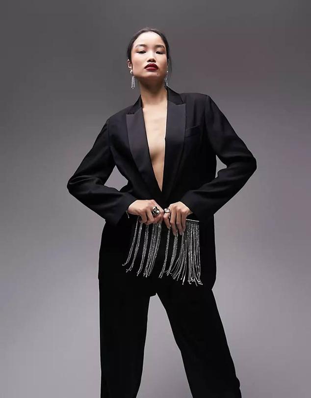 Traje con americana de smoking con solapas satinadas y pantalón ancho, color negro, de Topshop. Te costará 85,99 euros y 52,99 euros, en Asos.