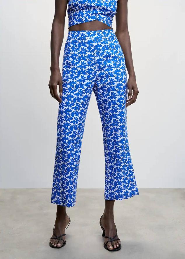 Pantalón de algodón con tiro alto, corte entallado y perneras cropped, en floral print azul, de Mango. Cuesta 35,99 euros.