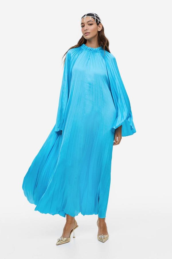 Vestido en tejido plisado suave con corte relajado, cuello con volante y mangas raglán larga con maxi volumen, color turquesa. Su precio es de 69,99 euros.