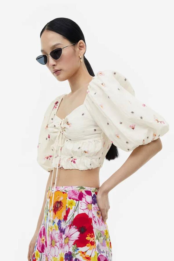 Top cropped con escote corazón, mangas corta abullonadas, detalles fruncidos, lazada y mini estampado, en crudo, de H&M. Cómpralo por 24,99 euros.