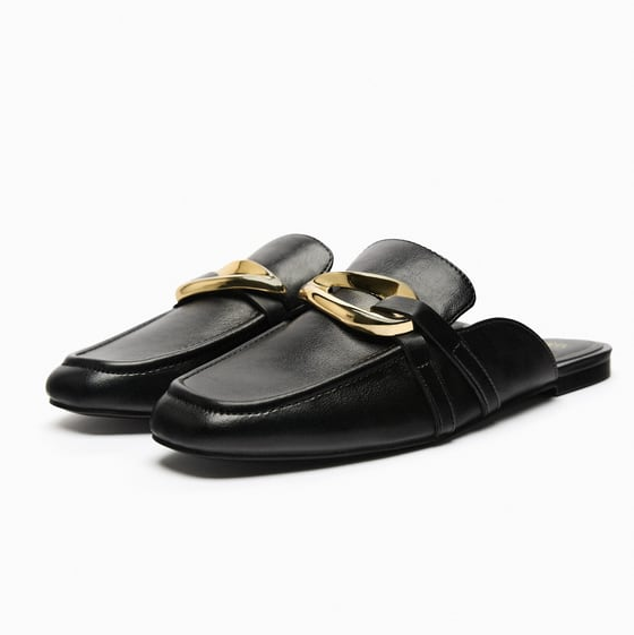 En Zara hay unos mules negros muy parecidos que tienen una hebilla dorada en el empeine como detalle diferenciador. Y cuestan tan solo 15,99 euros.