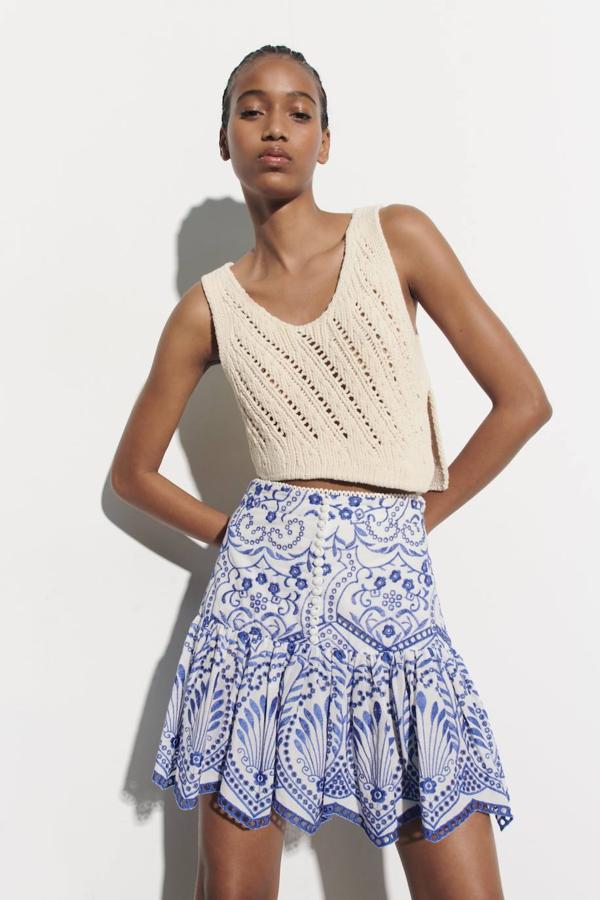 Falda corta con tiro alto, detalles de bordados y perforados, bajo terminado en volantes y botones en el delantero, en blanco y azul. Cómprala por 29,95 euros.