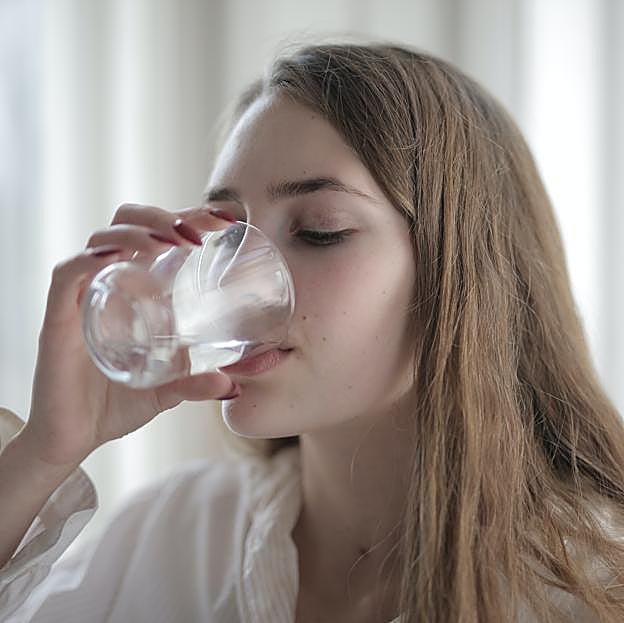 Mujer bebiendo un vaso de agua.