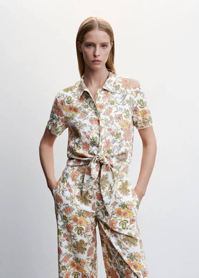 Camisa de lino con manga corta, cuello solapa, cierre de botones, lazo decorativo y floral print multicolor, de Mango. Puedes comprarla por 22,99 euros.